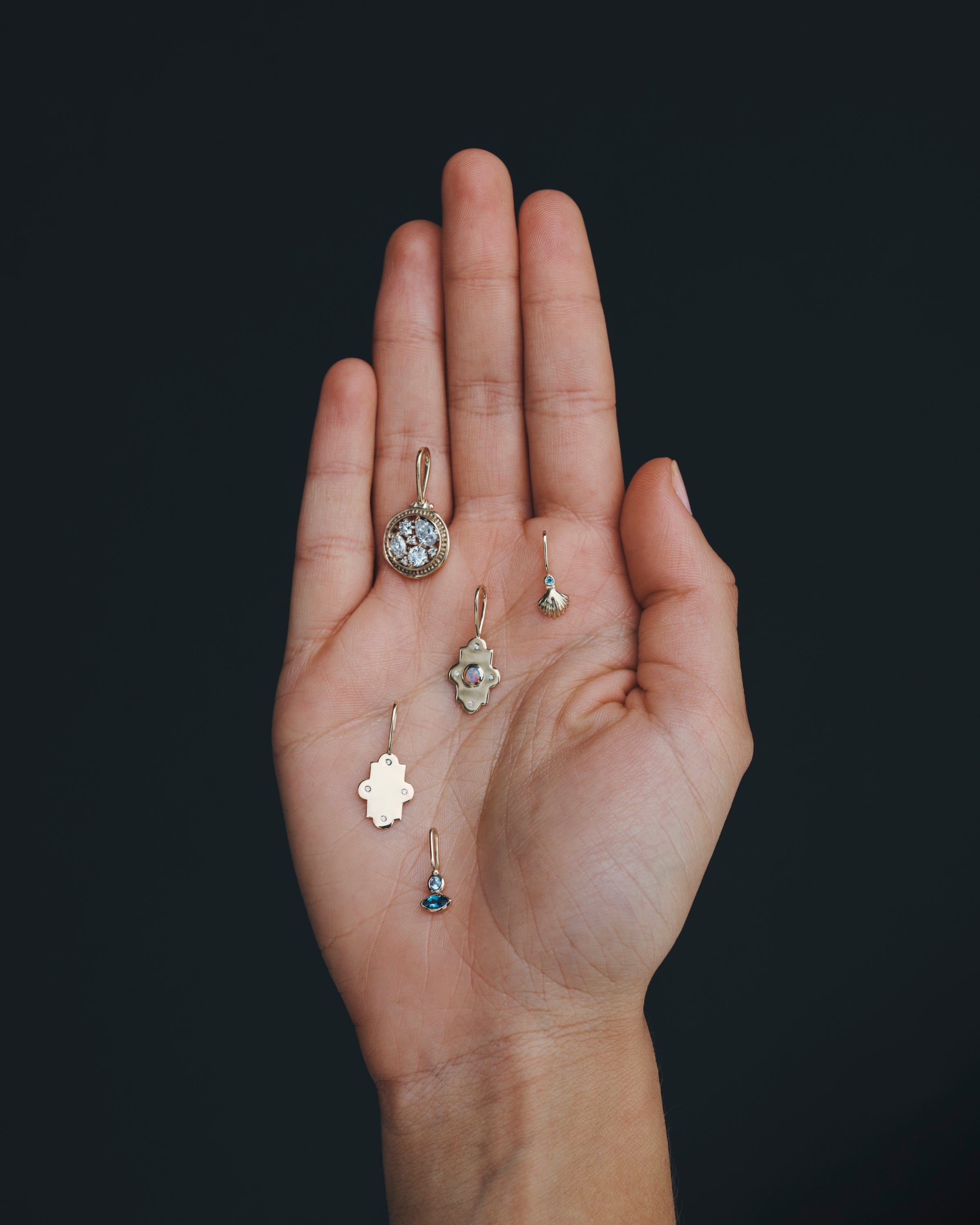 Hand holding multiple earrings against a black background