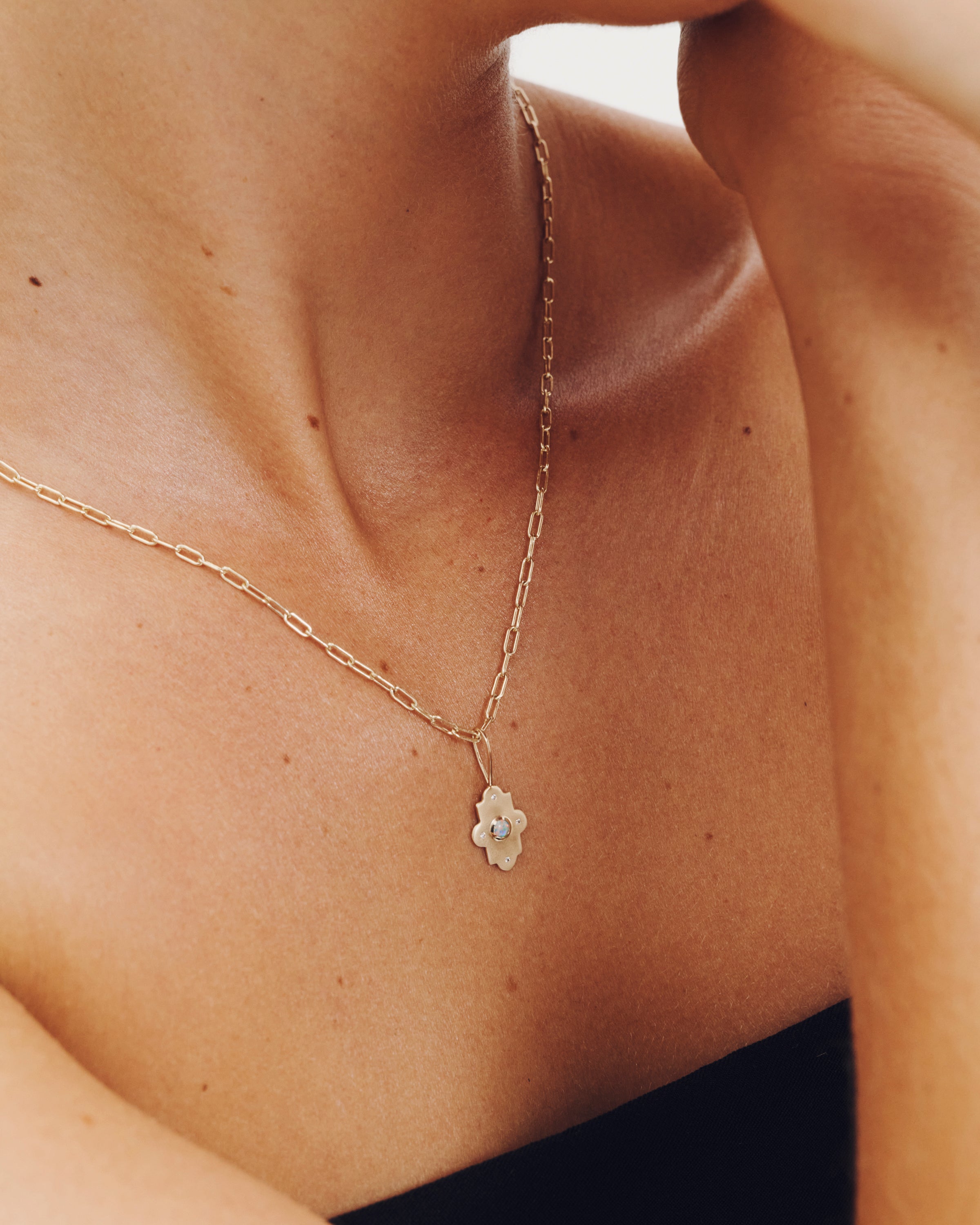 Gold necklace with a floral pendant on a person's neck