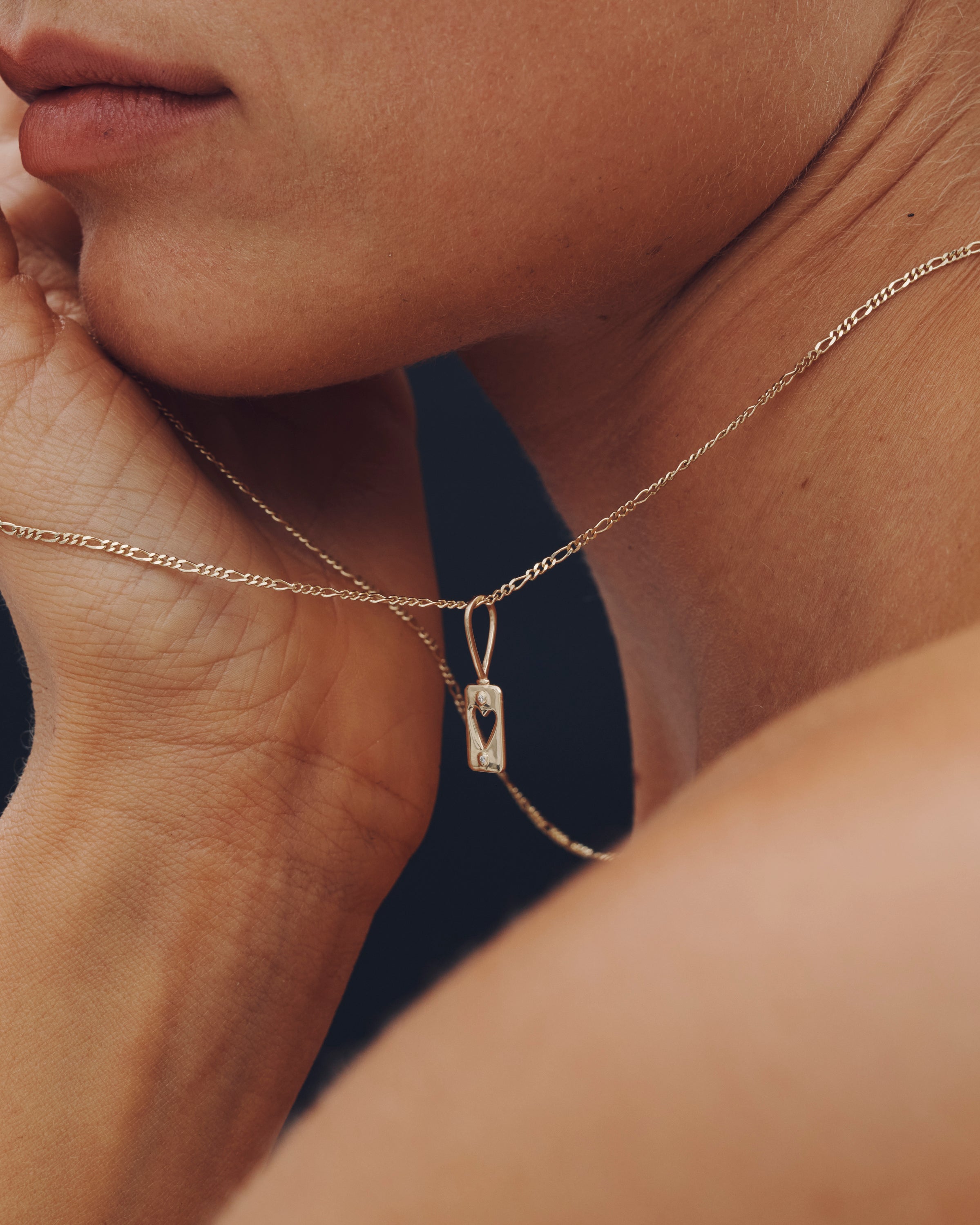 Close-up of a person wearing a gold necklace with a pendant.