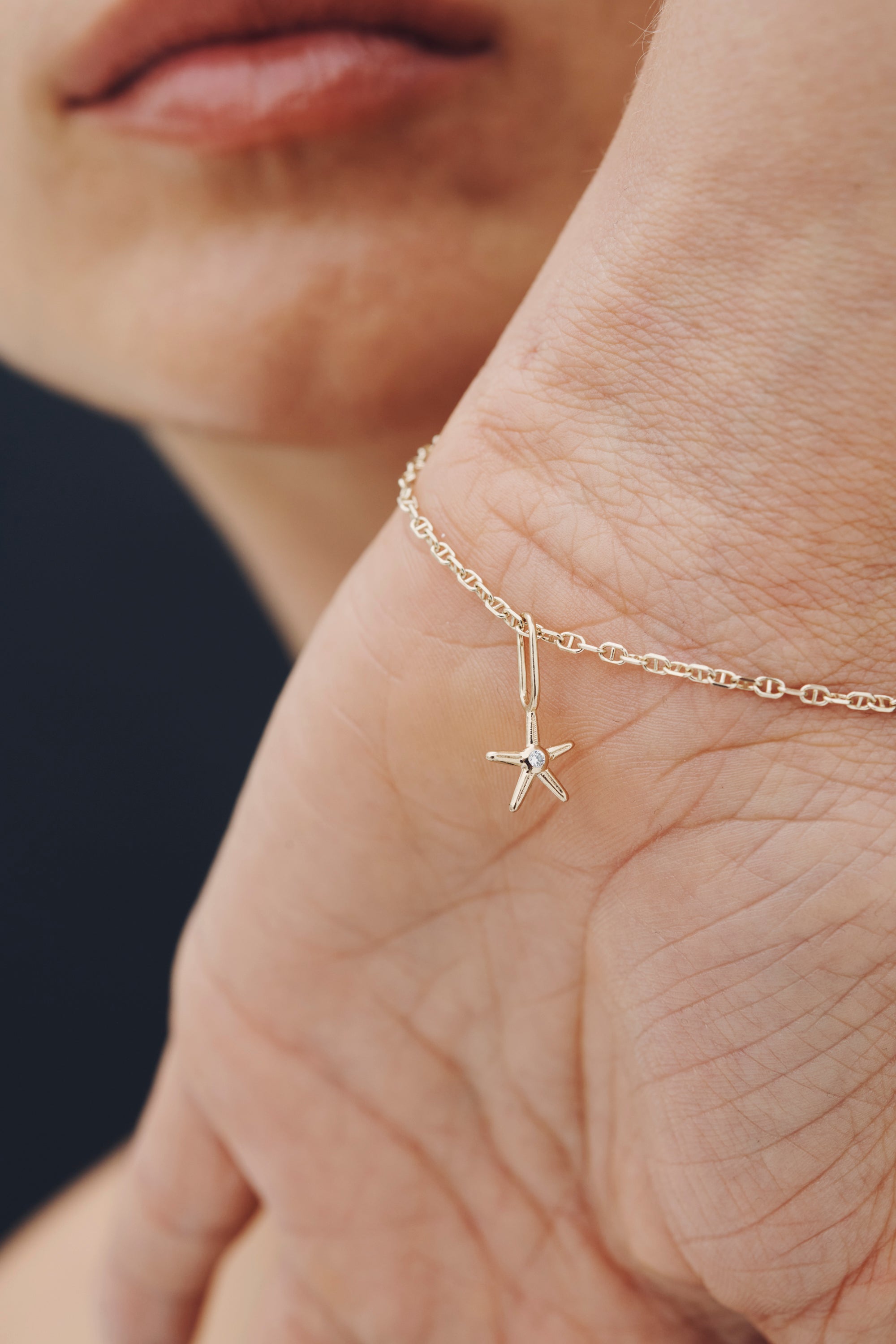 Close-up of a gold bracelet with a star-shaped pendant on a person's wrist.