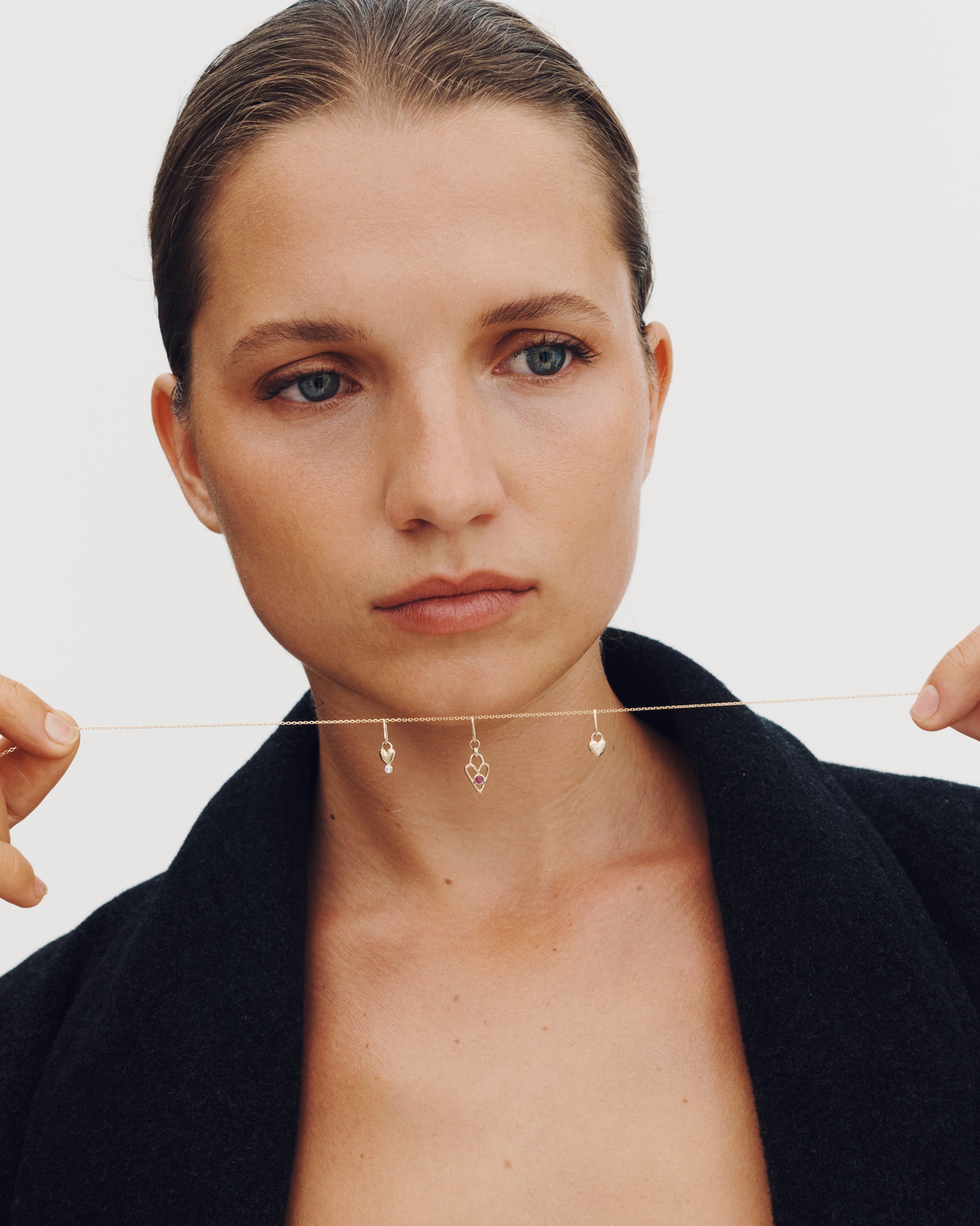 Woman balancing a string on her face with earrings on a plain background