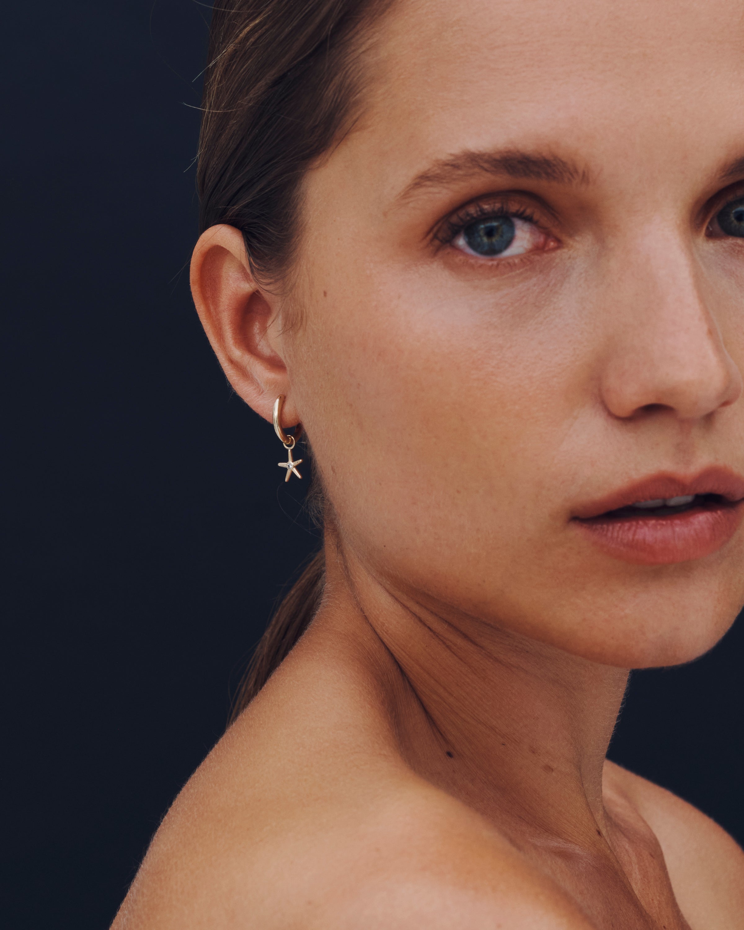 Close-up of a woman wearing a starfish earring against a dark background