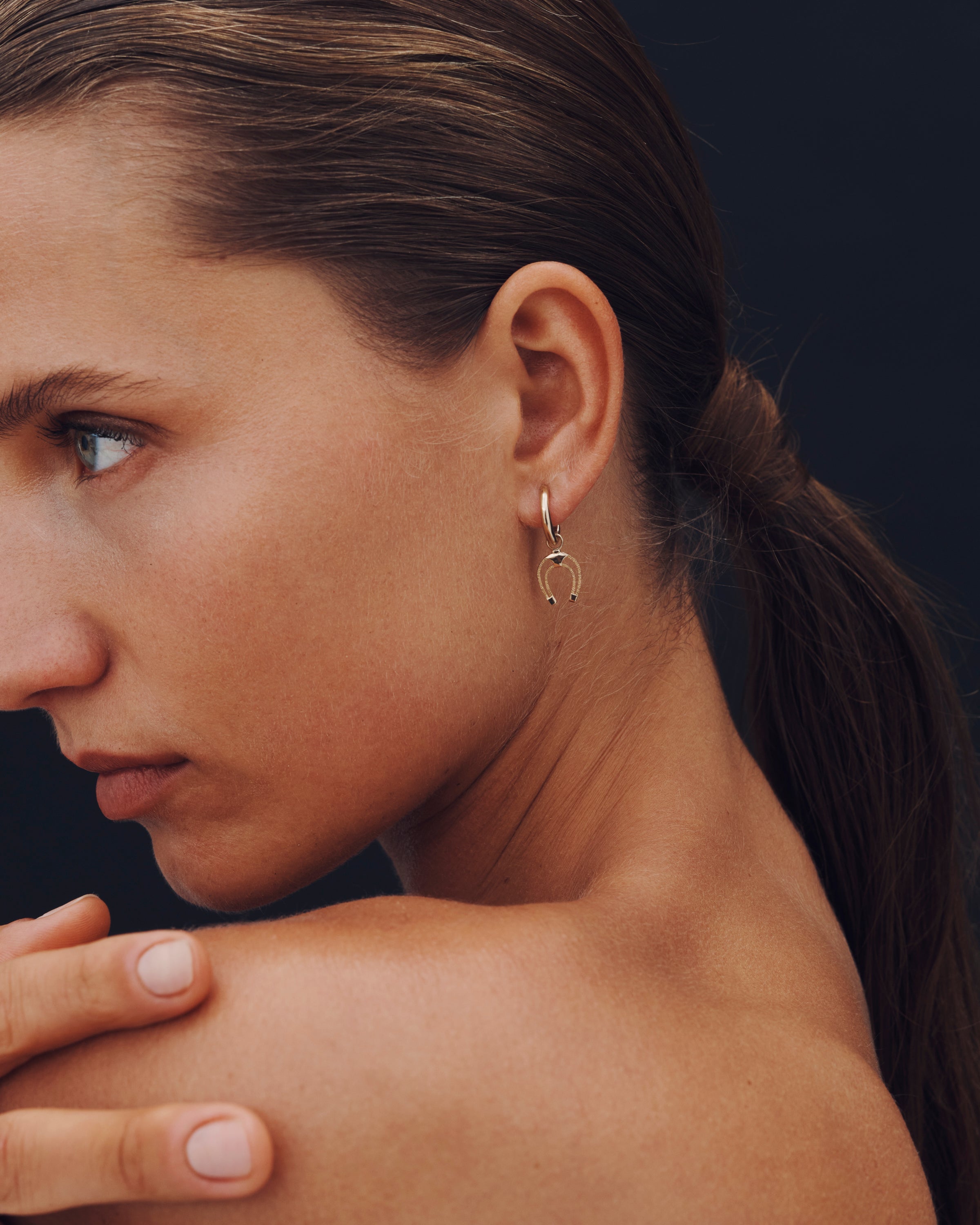 Close-up of a woman wearing a gold earring with a dark background
