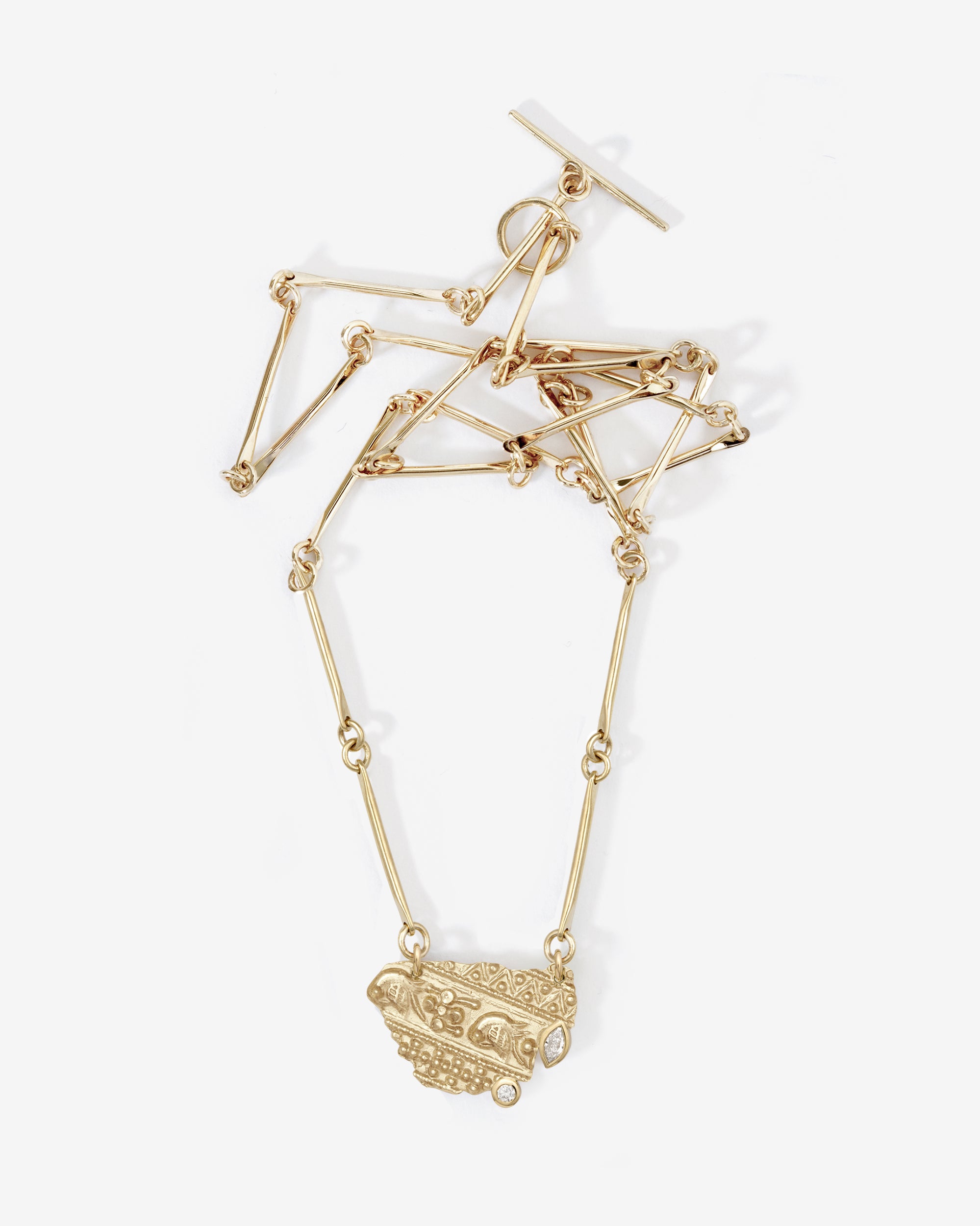 Gold necklace with geometric pendant on a white background