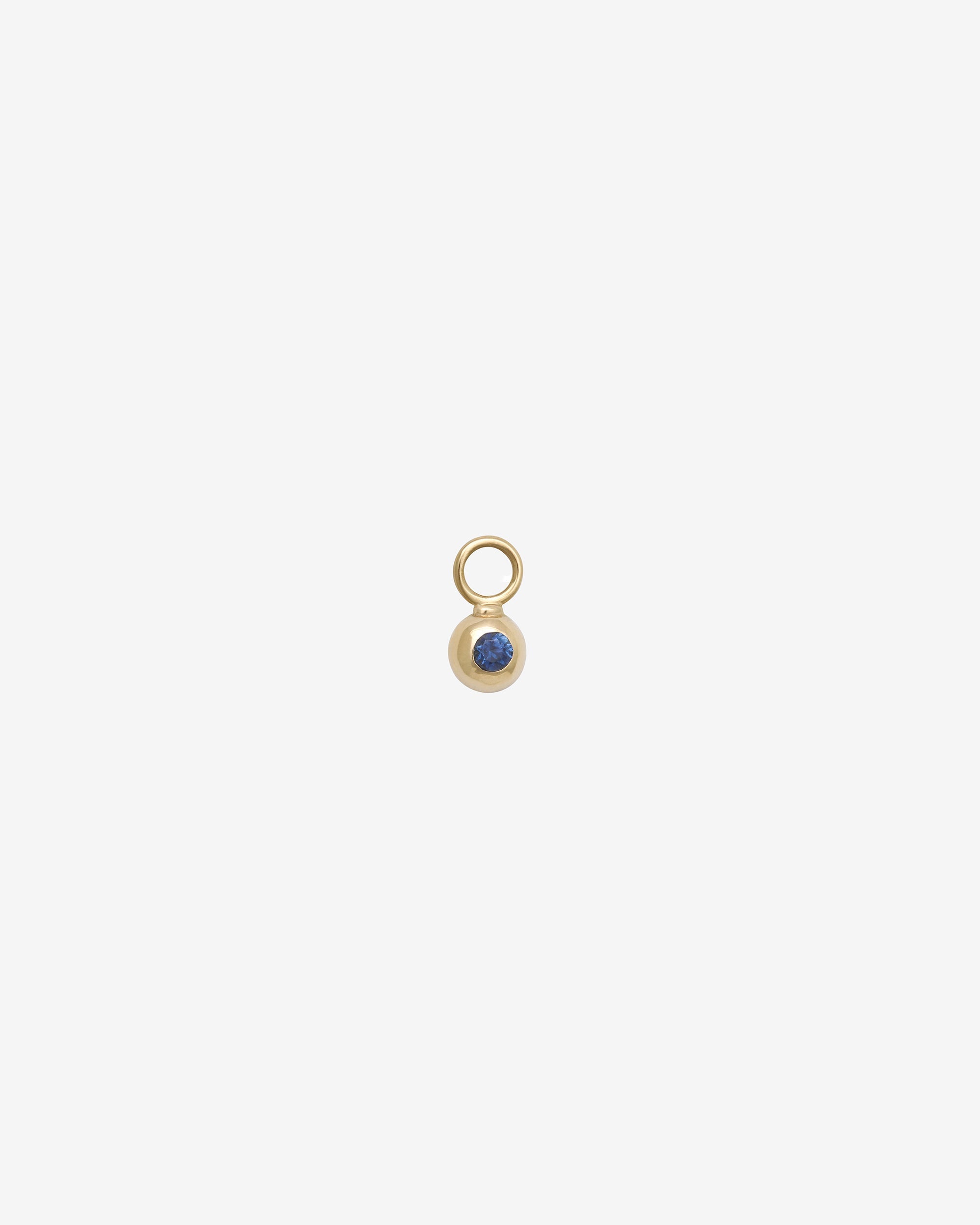 Gold charm with a blue gemstone on a white background