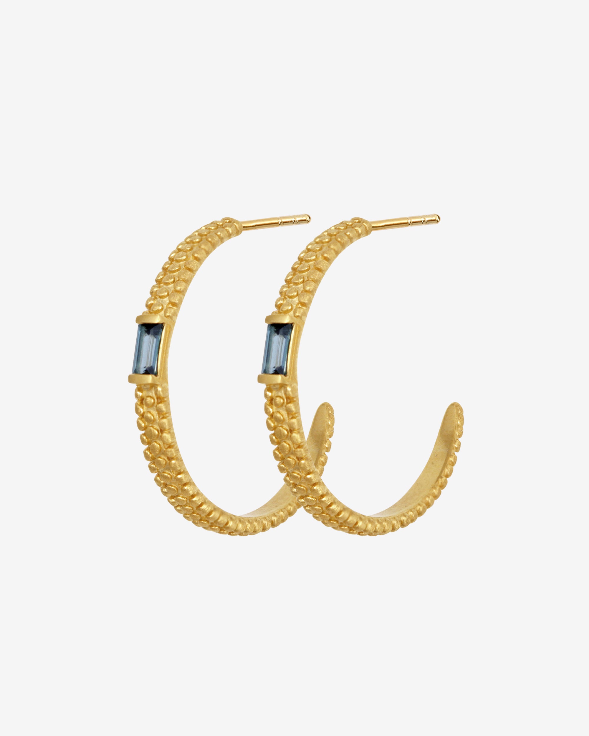 Gold hoop earrings with blue gemstones on a white background