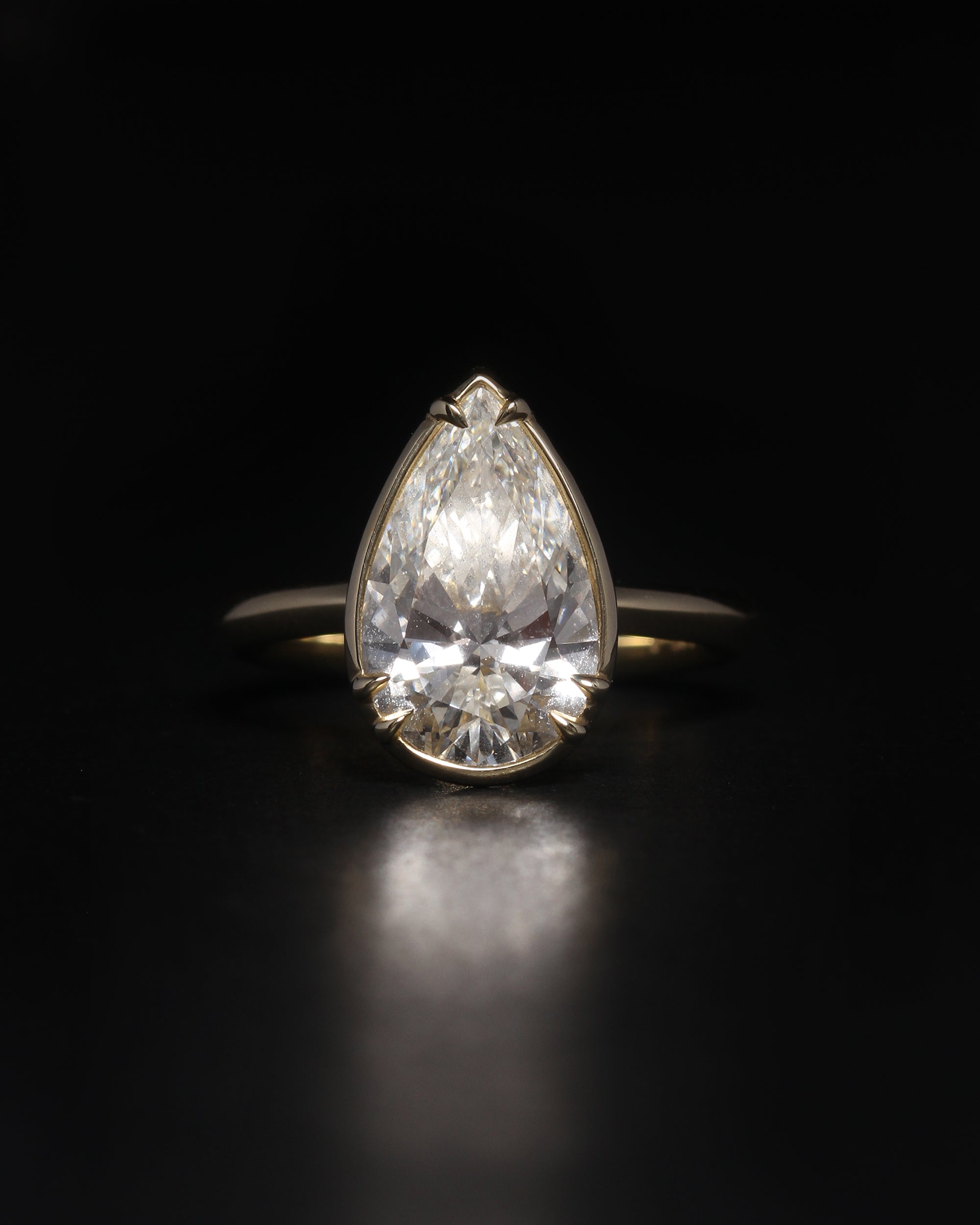 Gold ring with a large pear-shaped diamond on a black background