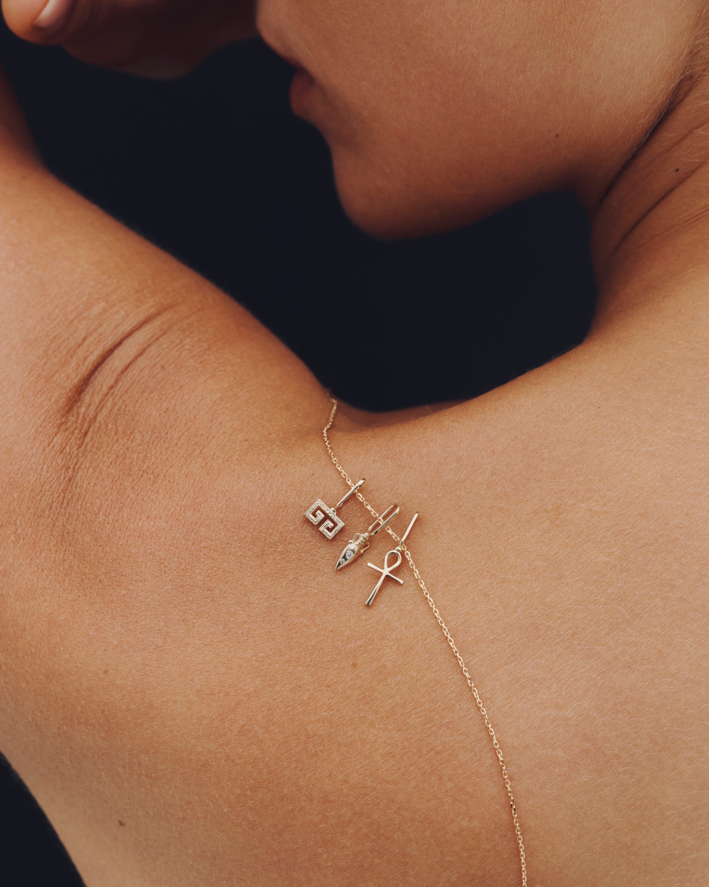 Gold necklace with charms on a person's chest