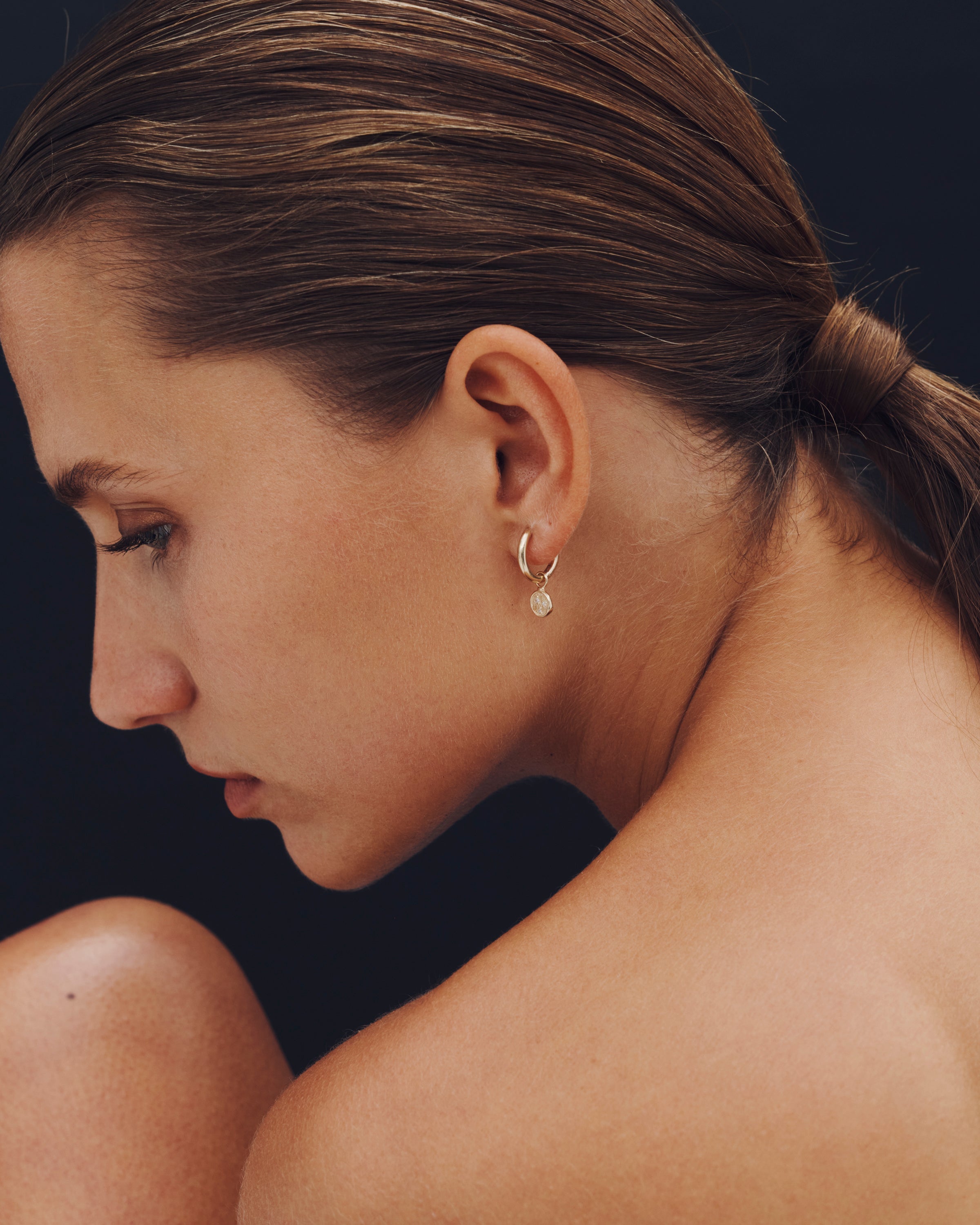 Close-up of a woman wearing a hoop earring with a dark background